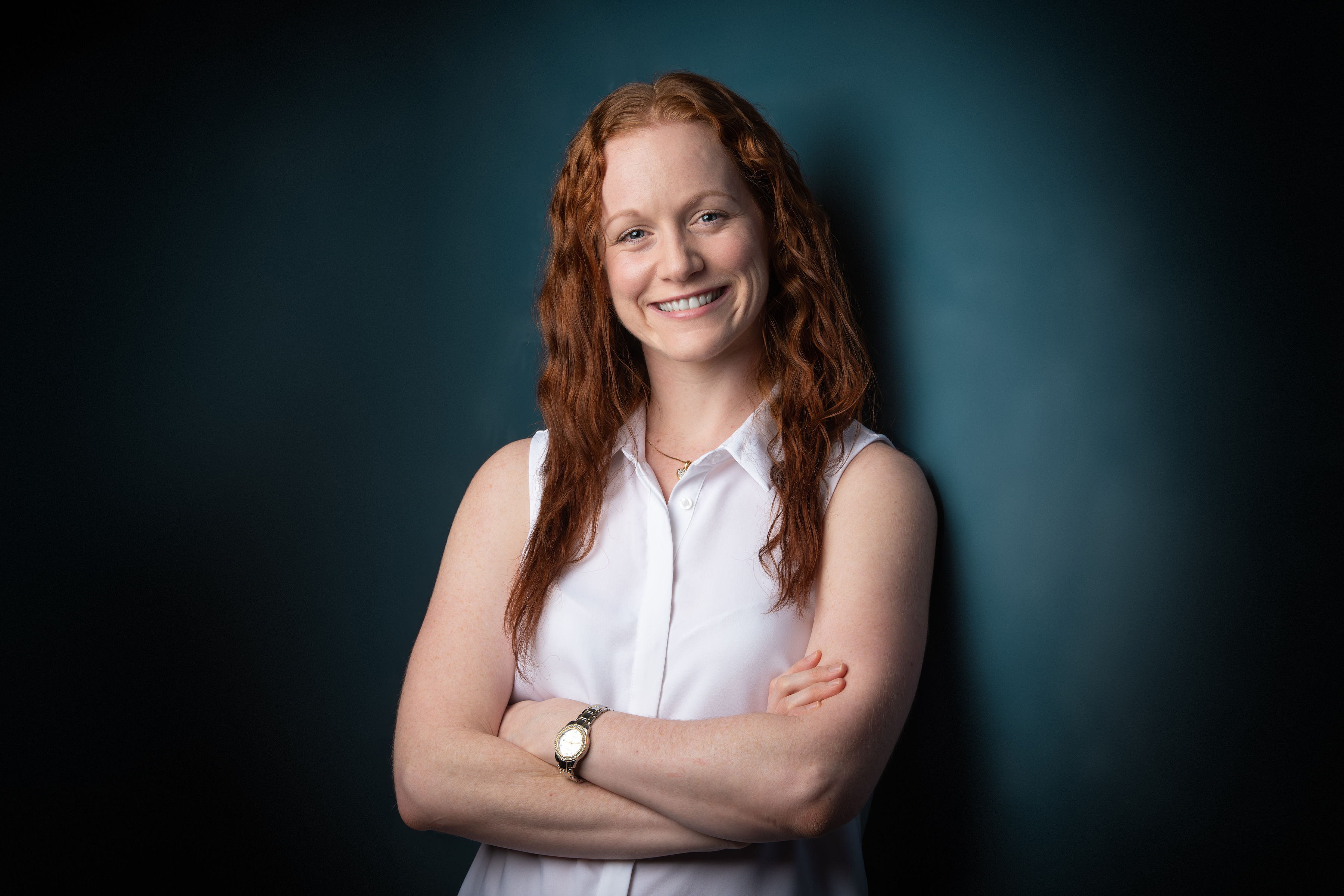 Photo of Amanda Webster from the waist up. Her arms are crossed underneath her chest, and she has a wide smile.